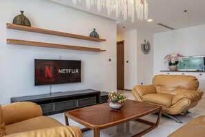 Ein Wohnzimmer mit einem Flachbildfernseher, der das Netflix-Logo zeigt, einer Ledersofa, einem Holztisch und einer dekorativen Vase.