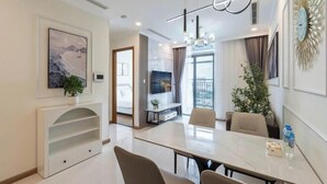A modern hotel room with a dining area, a TV, and a large window. - The Peninsula Apartment Landmark (Ho Chi Minh City)