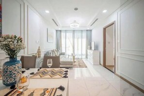 Una habitación de hotel moderna con zona de comedor, sofá y televisor.