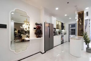 A modern kitchen with a large island, stainless steel appliances, and a unique mirror design. - The Peninsula Apartment Landmark (Ho Chi Minh City)