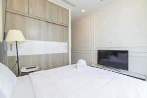 Una camera d'albergo con un letto, una TV, una lampada, un comodino e un armadio.