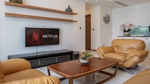 A modern living room with a leather sofa, a wooden coffee table, and a flat-screen TV mounted on the wall. - The Peninsula Apartment Landmark (Ho Chi Minh City)