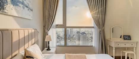 Un dormitorio con cama, tocador con espejo y vistas a la ciudad a través de una ventana.