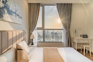 Un dormitorio con cama, tocador con espejo y vistas a la ciudad a través de una ventana.