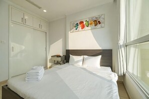 Una camera d'albergo con un letto, un armadio, un comodino e una finestra con tende.