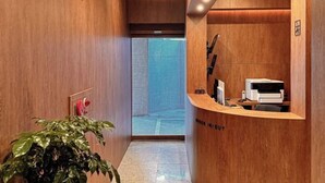 A reception area with a wooden reception desk, a printer, and a potted plant. - Hotel Emok (Busan)