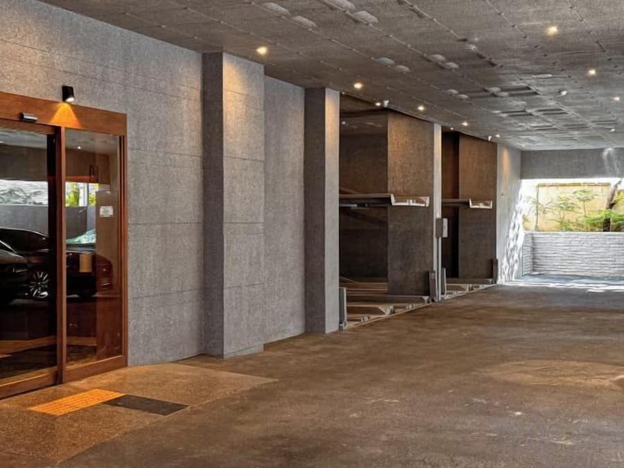 A modern building with a concrete floor and walls, a glass door entrance, and a visible staircase.