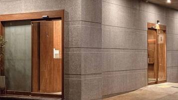 Two wooden elevator doors with a textured wall and a concrete floor.