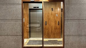 An elevator with a wooden exterior and a digital display showing the floor number 5. - Hotel Emok (Busan)
