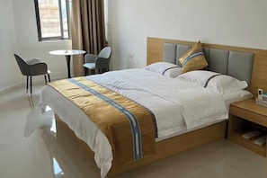 A hotel room with a bed, bedside table, and two chairs. - Five Tigers Hotel (Boten)