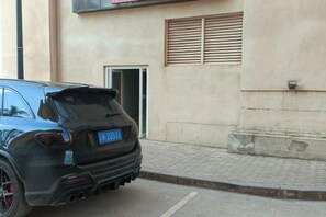 A black SUV parked in front of a building with a visible door and window.