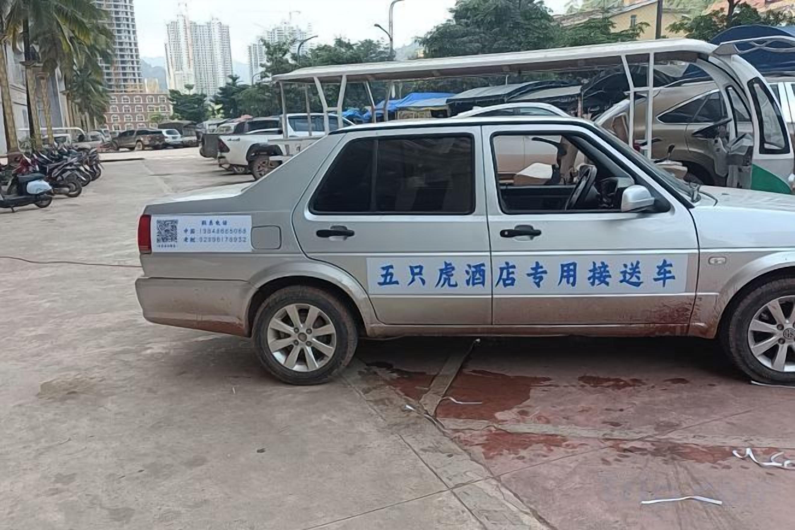 A silver car parked on a street with visible text on the side.