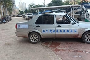 A silver car parked on a street with visible text on the side. - Five Tigers Hotel (Boten)