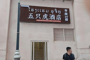 A hotel sign with contact information and a window with a door. - Five Tigers Hotel (Boten)