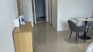 A hotel room with a wooden desk, a round table with a chair, and a door leading to a bathroom. - Five Tigers Hotel (Boten)