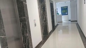 A hallway with marble walls and a shiny tiled floor. - Five Tigers Hotel (Boten)