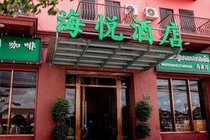 A hotel entrance with a green signboard, a covered entrance, and potted plants. - HaiYATT Hotel (Phnom Penh)