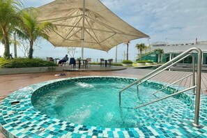 A swimming pool with a tiled edge, a metal ladder, and an umbrella providing shade. - Imperium Residence Kuantan by Iconique (Kuantan)