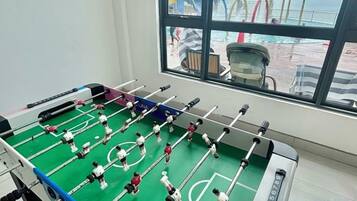 Uma mesa de futebol de mesa em um quarto com uma janela grande que dá para uma área de deck.