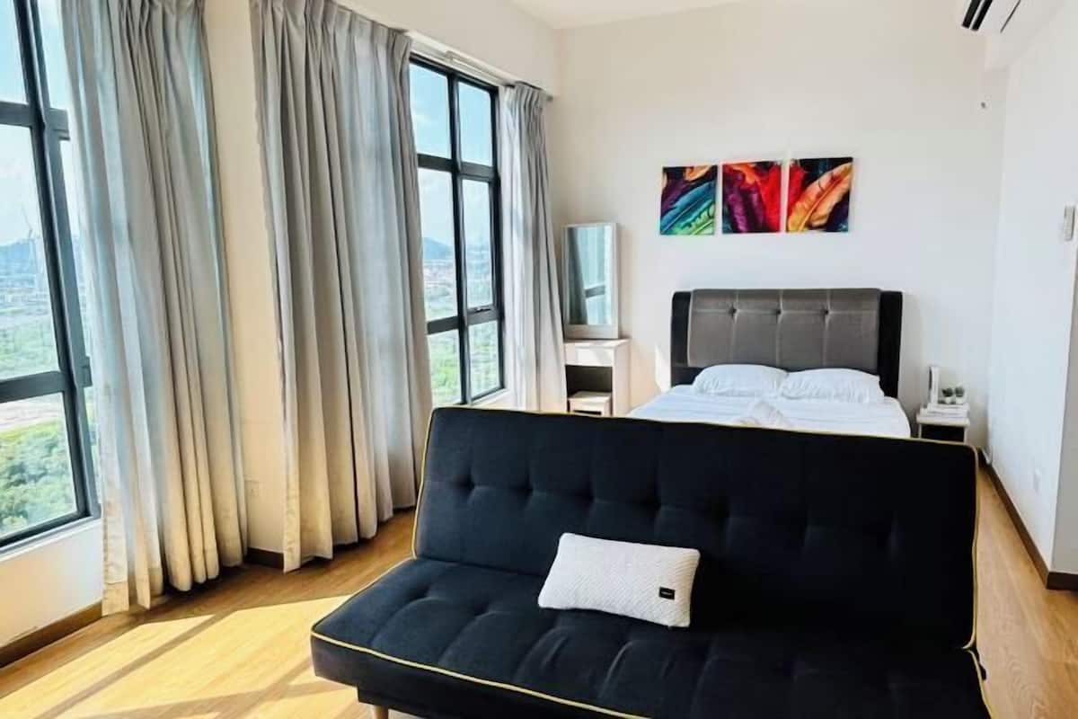 A hotel room with a large bed, a sofa, a TV, and a painting on the wall.