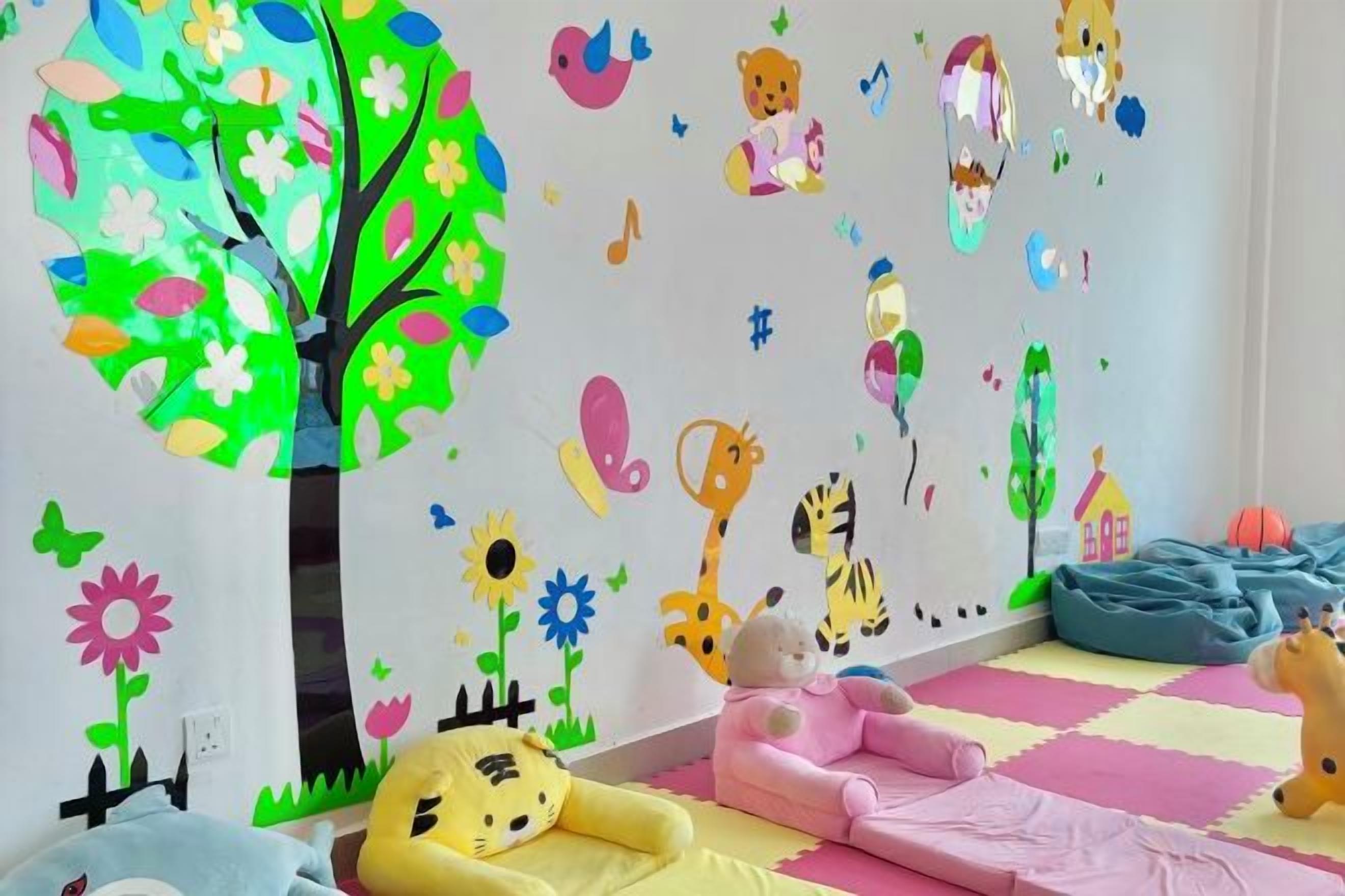 A child's playroom with a wall decorated with colorful stickers, a pink play mat, and a blue bean bag.