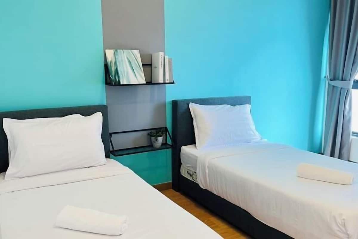 A hotel room with two beds, a bookshelf, and a window with curtains.