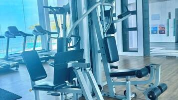 A gym with exercise equipment, a treadmill, and a large window with a view.