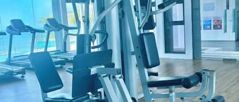 A gym with exercise equipment, a treadmill, and a large window with a view.