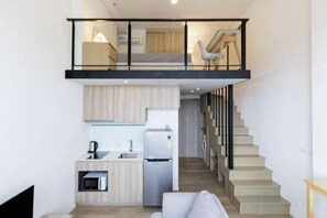 Un appartement moderne comprenant une cuisine, un coin repas et un escalier menant à une chambre en mezzanine.