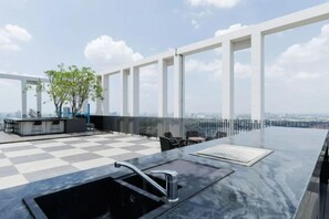 A rooftop terrace with a checkered floor, a bar area, and a seating arrangement. - Bangkok Sukhumvit 87 Boutique Apartment (Bangkok)
