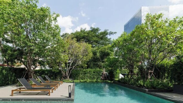 A swimming pool with lounge chairs and lush greenery.