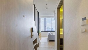 A modern hallway with a wooden floor, a built-in bench, and a large window offering a city view.