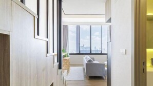 A modern interior with a sofa, wooden paneling, and a view through large windows.