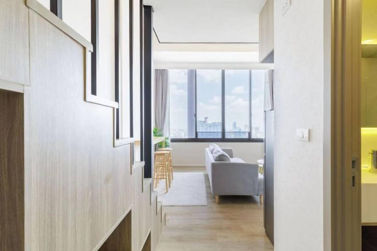 Ein modernes Interieur mit einer Couch, Holzvertäfelung und Blick durch große Fenster.