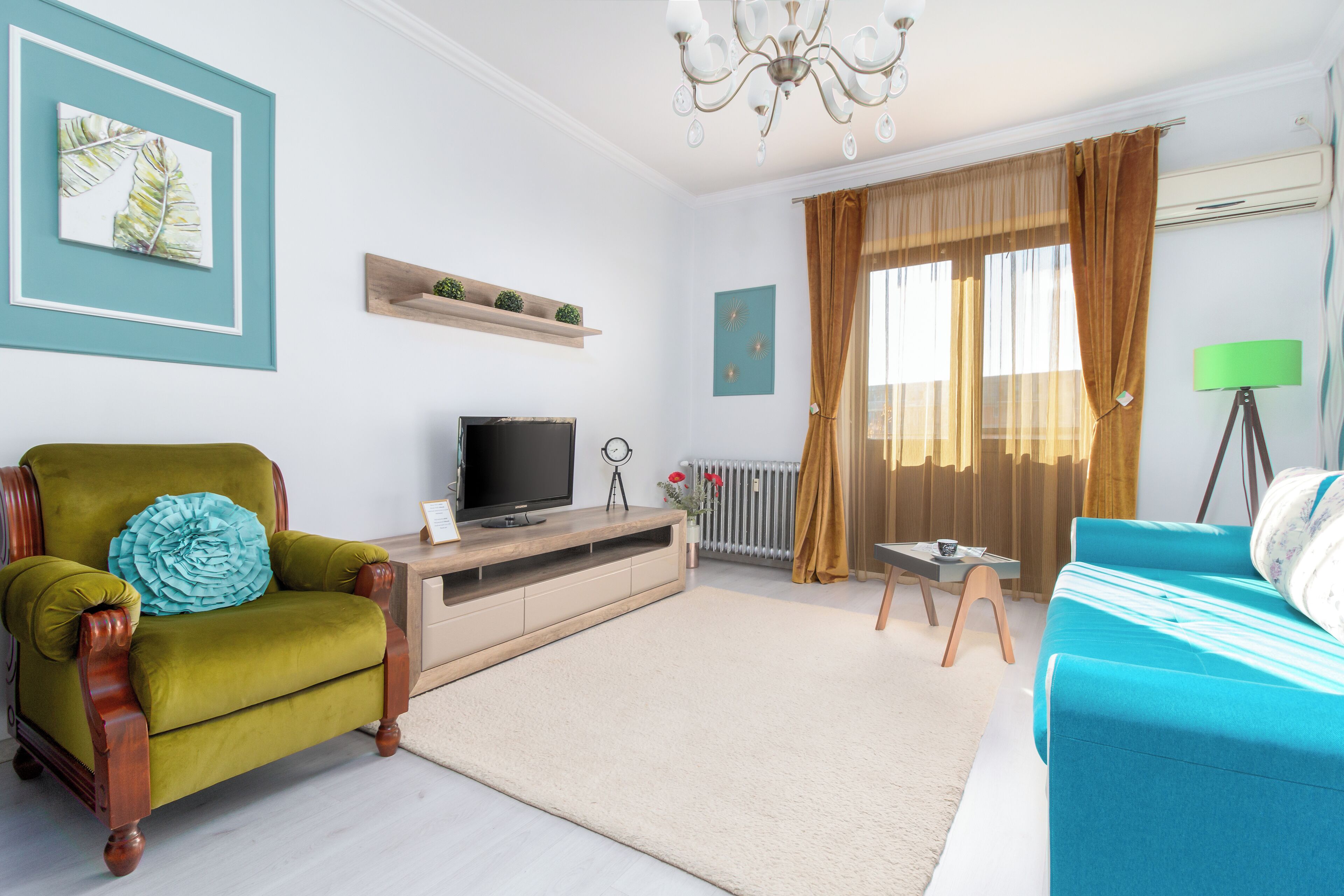A living room with a green armchair, a blue sofa, a television, and a radiator.
