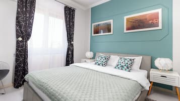 A modern bedroom with a bed, nightstands, and a desk.