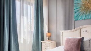 Une chambre à coucher avec un lit, une table de chevet avec une lampe et une œuvre d’art accrochée au mur.