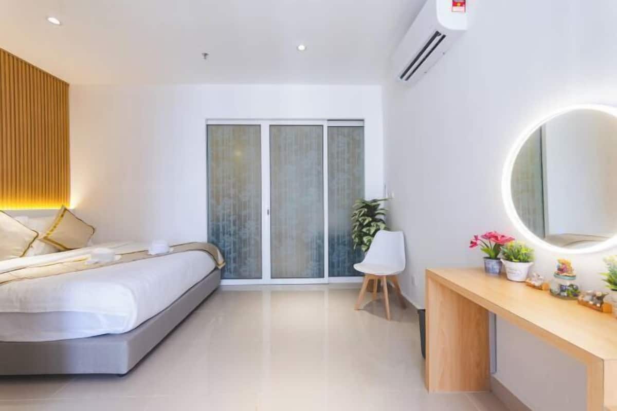 Une chambre à coucher moderne avec un lit, un bureau, une chaise, un miroir et une plante en pot.