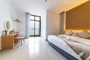 Une chambre d’hôtel moderne, dotée d’un grand lit, d’un bureau avec une chaise, d’un miroir et offrant une vue sur l’extérieur.