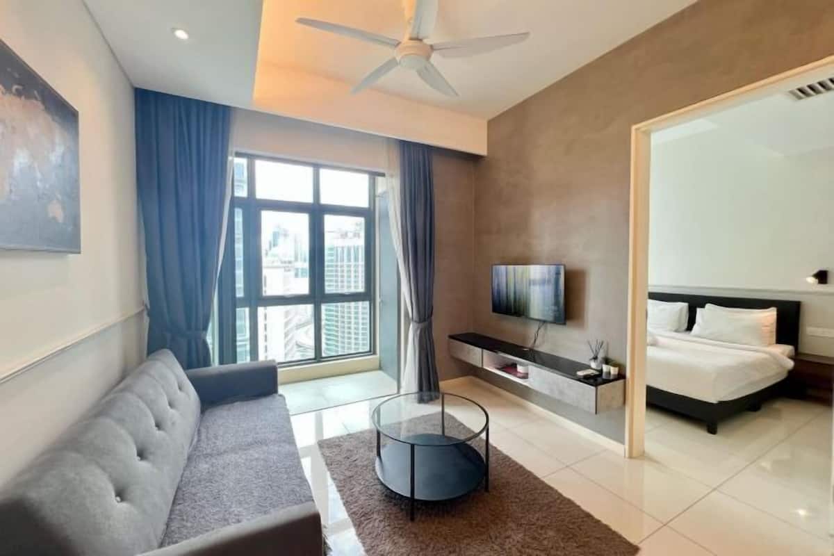 Een moderne hotelkamer met een bank, een televisie, een bed en een groot raam.