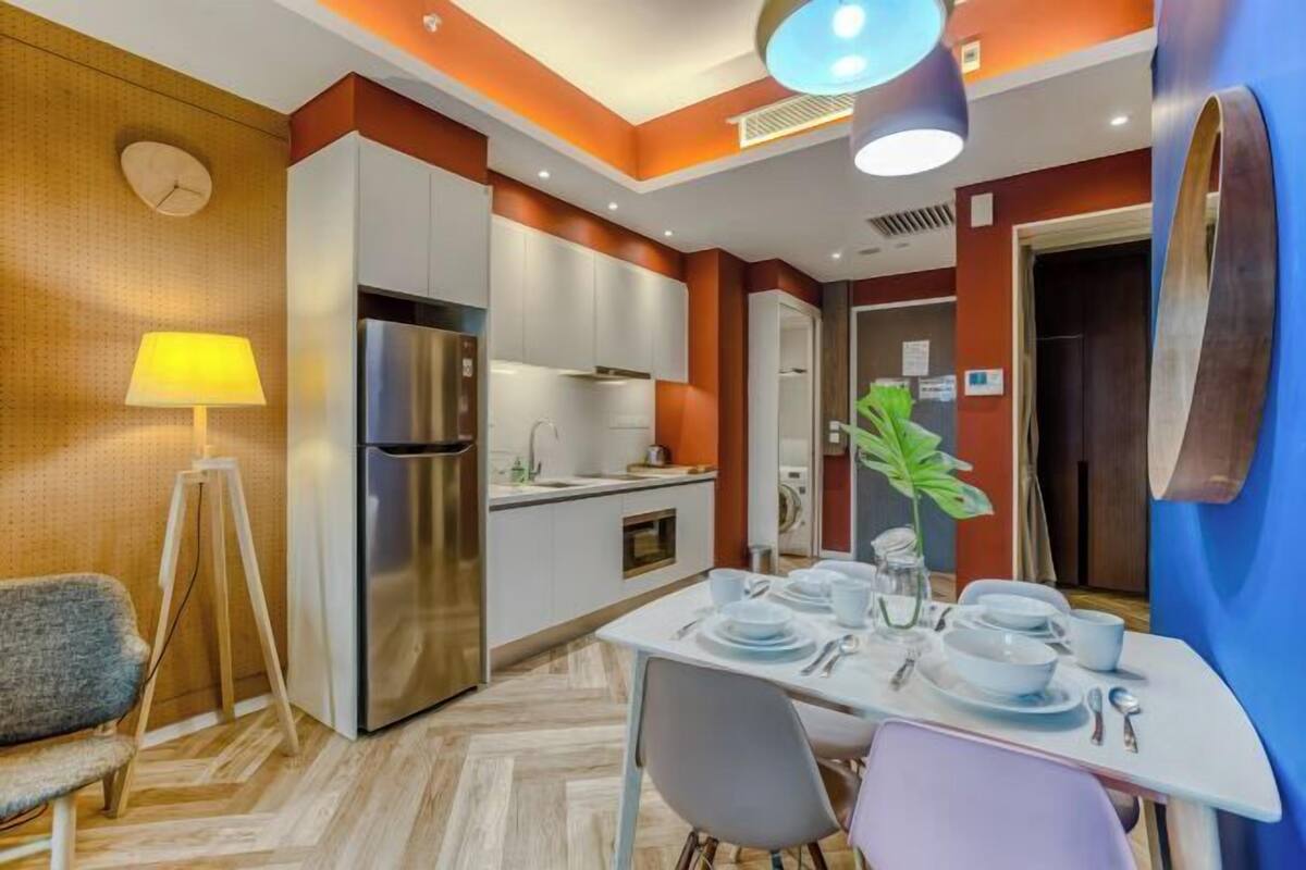 Een moderne keuken met witte kastjes, een roestvrijstalen koelkast en een eethoek met een tafel gedekt voor twee personen.