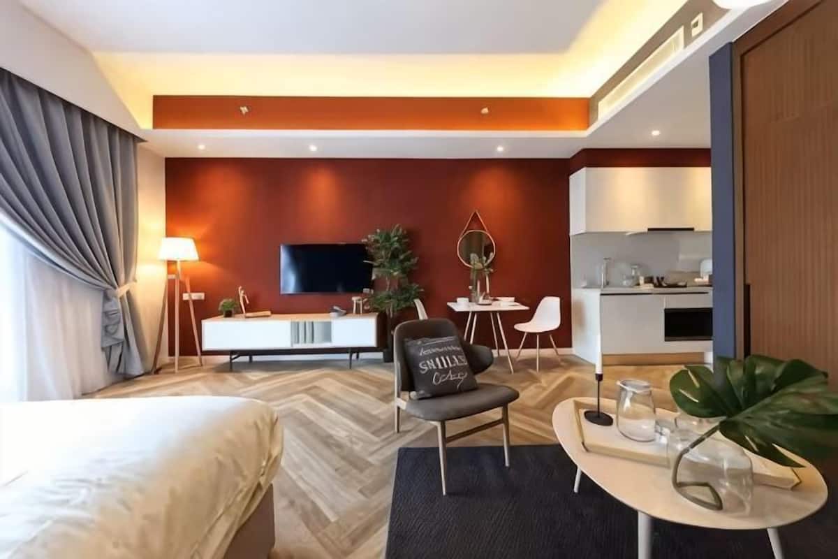 Een hotelkamer met een bed, een bureau, een televisie, een eethoek en een keuken.