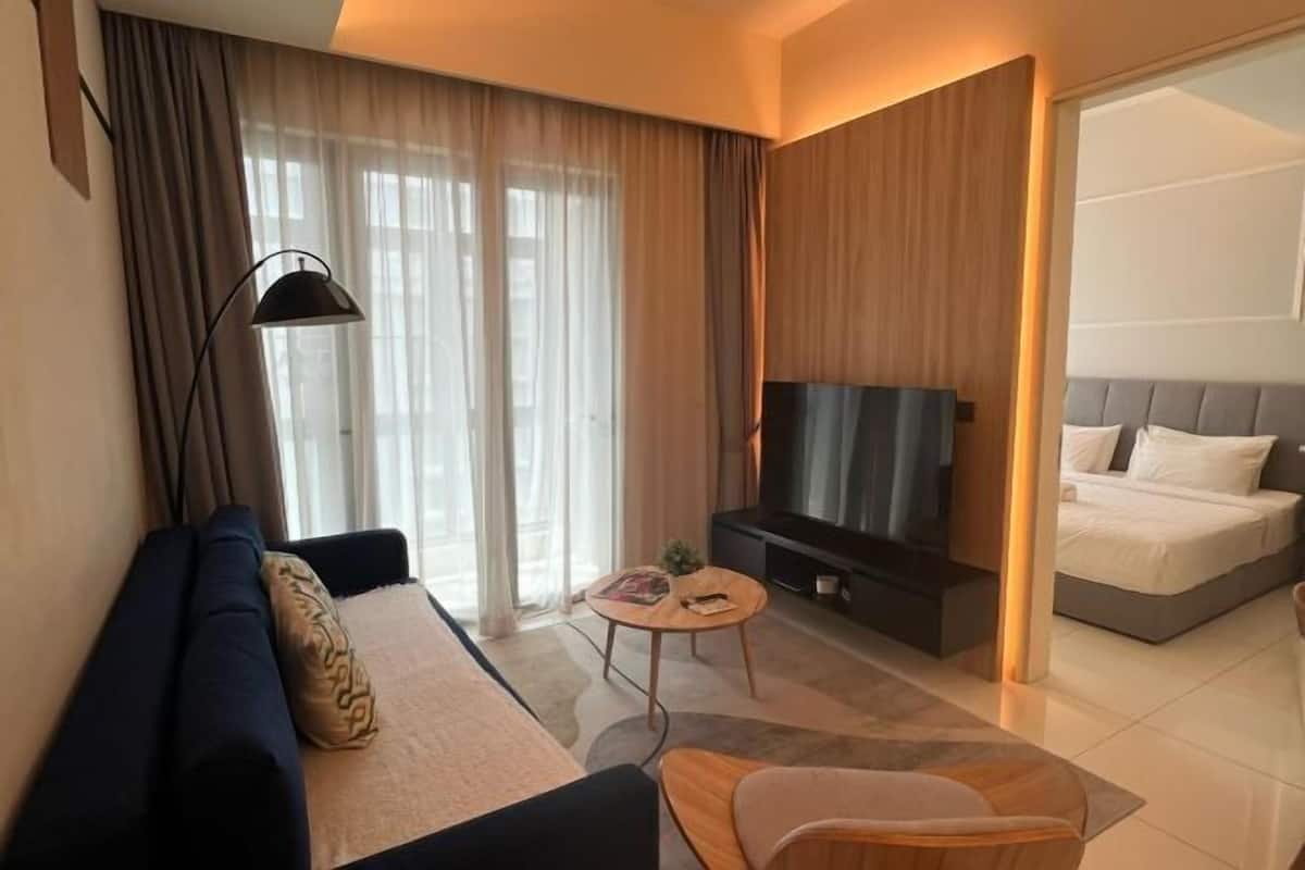 Een moderne hotelkamer met een bank, een klein rond tafeltje, een televisie en een bed.