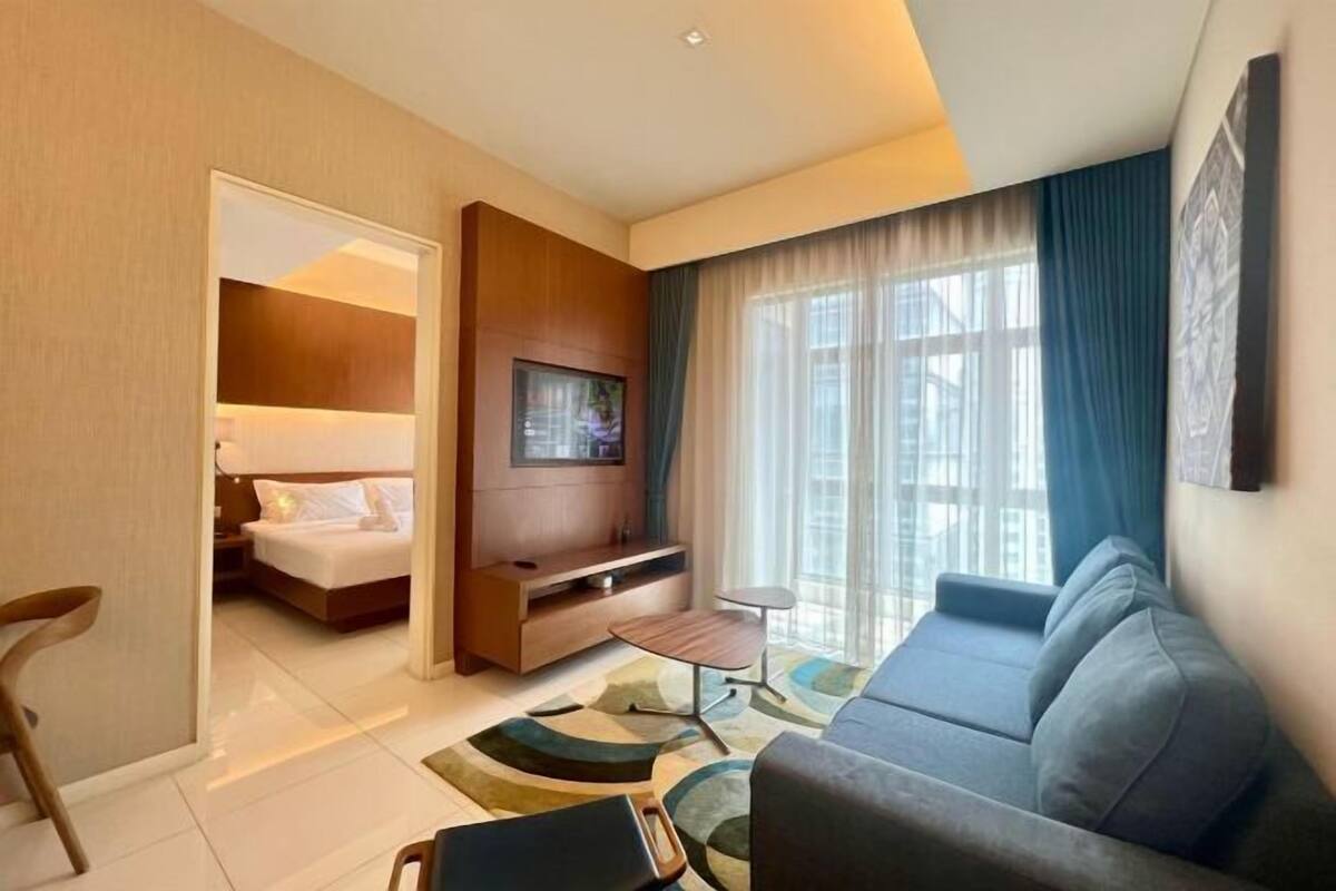 Een moderne hotelkamer met een bed, een televisie, een bank en een kleine tafel.