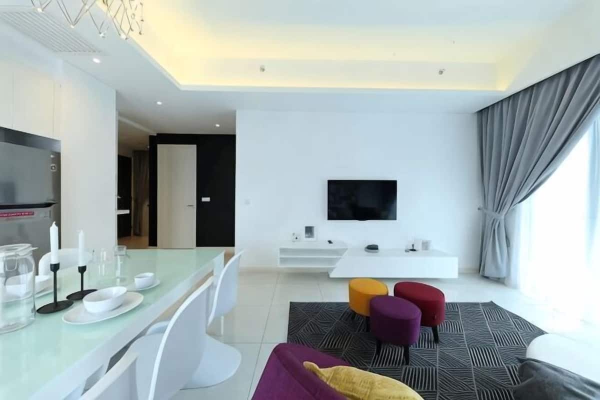 Een moderne hotelkamer met een zithoek, een televisie en een groot raam met gordijnen.