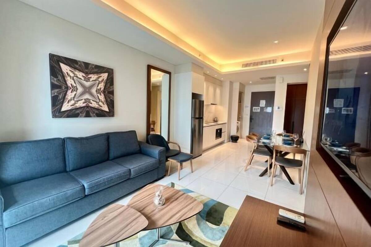 Een moderne woonkamer met een bank, salontafel en een eethoek met stoelen.