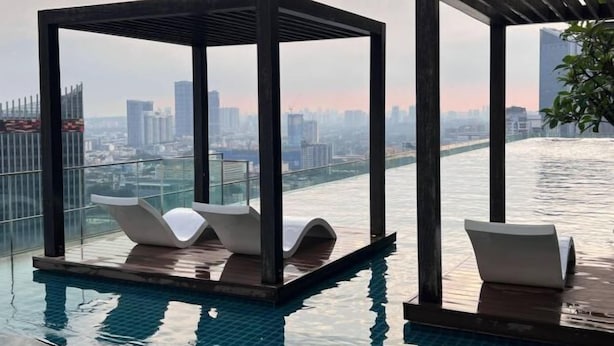 A rooftop infinity pool with two lounge chairs under a wooden pergola, overlooking a cityscape. - Tribeca Homestay Bukit Bintang TRX (Kuala Lumpur)