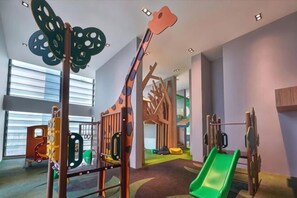 Un espace de jeux pour enfants avec un toboggan, des structures d’escalade et une décoration en forme de papillon.