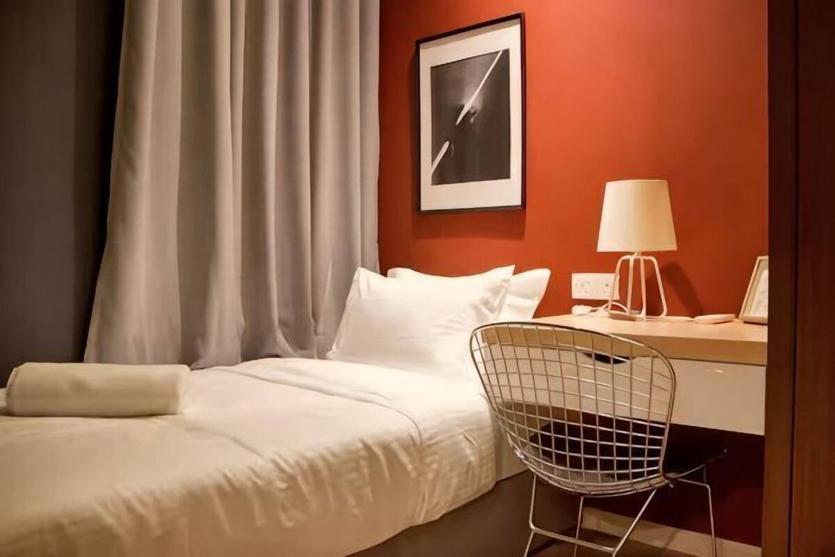 Een hotelkamer met een bed, een bureau, een stoel, een lamp en een lijst met een afbeelding aan de muur.