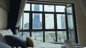 A hotel room with a large window, a bed, and a view of a cityscape. - Tribeca Homestay Bukit Bintang TRX (Kuala Lumpur)